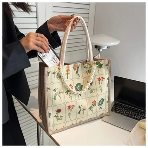 Detail of canvas tote bag showing pearl chain handle and spacious interior for phone