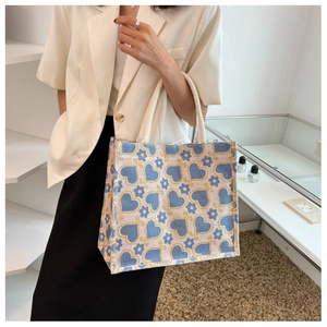 Detail of jute tote bag featuring blue heart and floral prints with cotton rope handles
