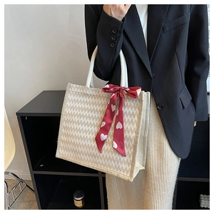 Détail du sac cabas en lin avec motif zigzag et ruban rouge à cœurs sur l'anse