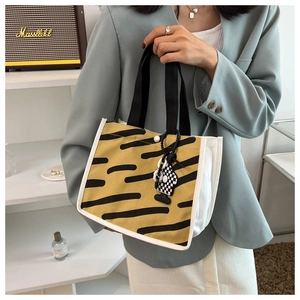 Detail of yellow tiger print canvas tote bag with black strap and checkerboard charm