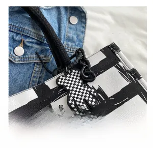Close-up of trendy checkerboard bear pendant decoration on a canvas shoulder bag