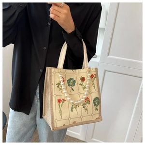 Detail of canvas tote bag with floral print and elegant pearl handle ornament