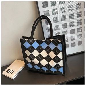 Detail of argyle canvas tote bag featuring blue and black patterns with woven handles