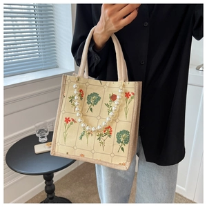 Detail of vintage floral canvas tote bag featuring an elegant large white pearl chain charm