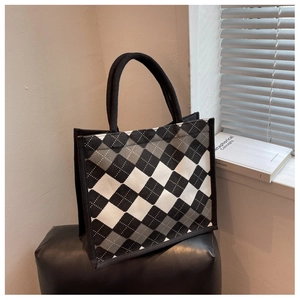 Detail of a large argyle knit tote bag with thick woven handles in a minimalist room