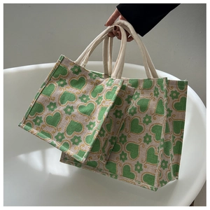 Detail of woven jute tote bags with green heart prints and thick cotton rope handles
