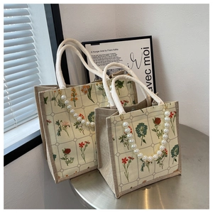 Close-up of vintage floral tote bag featuring elegant pearl and rope braided handles