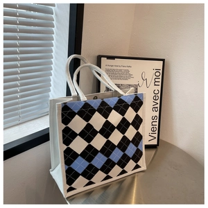 Detailed view of the argyle pattern canvas tote bag with woven rope handles and metal snap