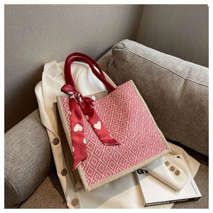 Close-up of beige linen tote bag with red diamond pattern and silk scarf on a sofa