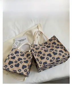 Detail of black canvas tote bags with heart pattern on a clean white bedding background