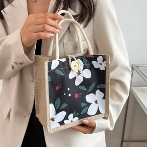 Sac à main carré à motif floral avec boucle en bois et poignée en corde porté par un modèle