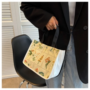 Close-up of floral canvas tote bag featuring daisy patterns and black straps