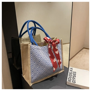 Detailed macro of a linen tote bag with blue diamond patterns and a red silk scarf detail