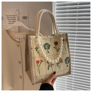 Detail of floral tote bag featuring a large pearl handle and woven cotton rope straps