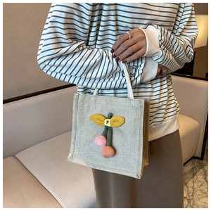 Detailed close-up of beige canvas lunch bag with 3D cherry and bow decor