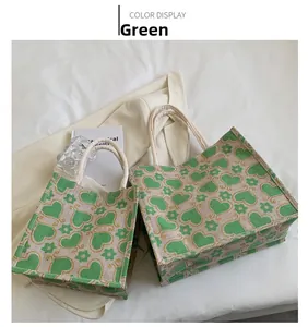 Detail of two floral canvas tote bags with green heart patterns on white shirt background