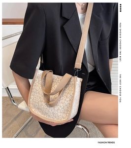 Fashionable beige canvas crossbody bag with white floral pattern on a female model