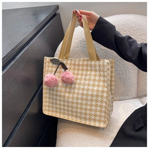 Detailaufnahme der gelben Hahnentritt-Tasche mit einem süßen rosa Kirsch-Plüsch-Anhänger