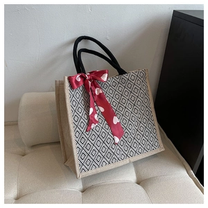 Linen tote bag detail with geometric patterns and red heart silk scarf on sofa