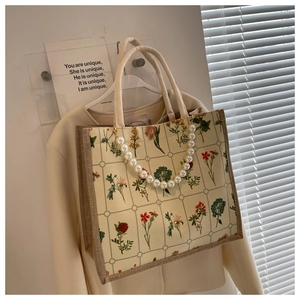 Close-up of canvas tote bag with floral grid pattern and elegant pearl chain handle