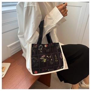 Detail view of the floral canvas tote bag featuring black fabric and a secure metal snap button