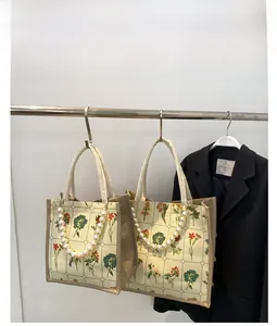 Detail of floral canvas tote bag with pearl chain handle and elegant plant prints