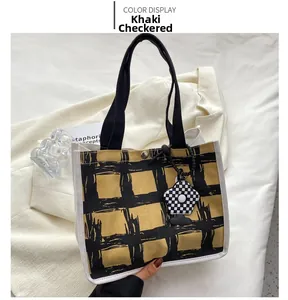 Detail of checkered khaki canvas tote bag with a flower charm and metal buckle closure