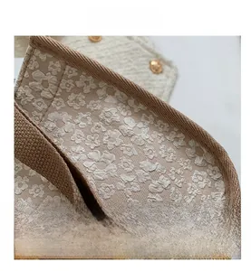 Detailed macro shot of floral jacquard fabric with brown woven edges and a gold button