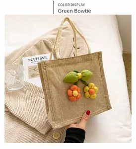 Detail of cute beige woven tote bag featuring a green knit bow and colorful floral accents