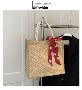 Detail of off-white woven tote bag featuring diamond textures and a red heart scarf