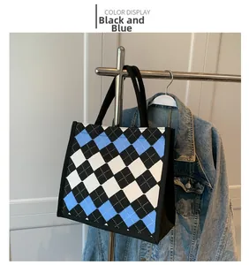 Detail of canvas tote bag featuring black and blue argyle pattern and woven strap