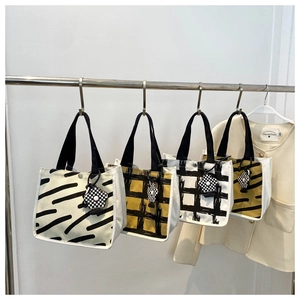 Detail view of canvas tote bags featuring zebra, grid, and wave patterns with floral charms