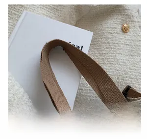 Detailed close-up of woven canvas handle and floral jacquard fabric on a stylish tote bag