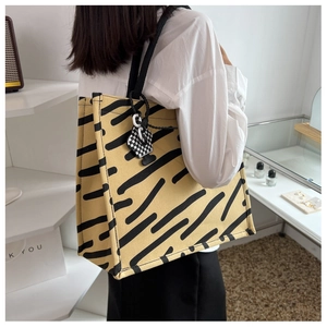 Dettaglio della borsa tote gialla a strisce nere con ciondolo a forma di fiore a scacchi