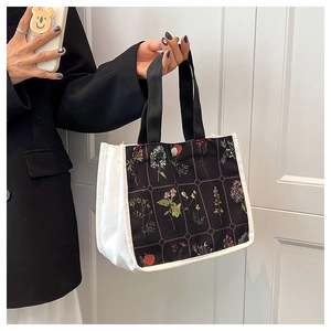 Close-up of canvas tote bag with black floral print patch and metal snap button closure