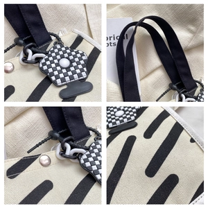 Detail view of canvas tote fabric textures with metal hardware and checkered flower charm