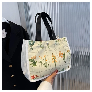 Detail of floral embroidery on grid canvas tote bag with black strap and metal snap closure