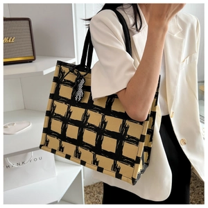 Detail of yellow and black checkered canvas tote bag with cute checkerboard bear charm