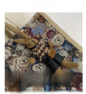 Detail of vintage knitted rabbit charm on woven tote bag with gold metal hardware