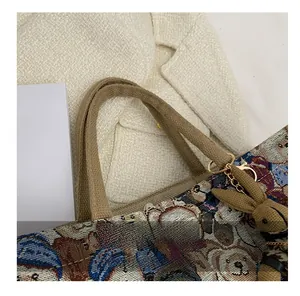 Detail of linen tote bag featuring woven bear patterns, thick handles, and a rabbit charm
