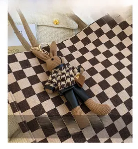 Close-up of a brown knitted rabbit charm with houndstooth outfit on a checkerboard tote bag