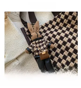 Detail of bunny doll charm with houndstooth sweater and leather pants with metal chain