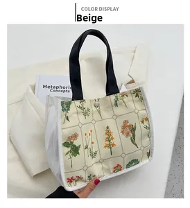Detail shot of beige floral canvas tote bag with black straps and metal snap closure
