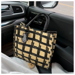 Detail of canvas tote bag with hand-drawn grid pattern and cute bear charm in car setting