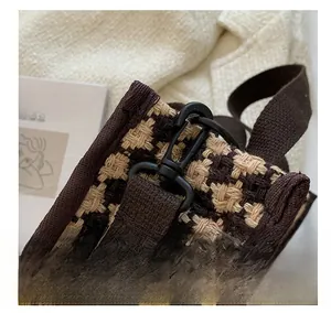 Detail of matte black metal hook and brown houndstooth woven fabric on shoulder bag