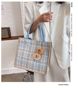 Detail of blue and white checkered tote bag with woven handles and plush charm accessory