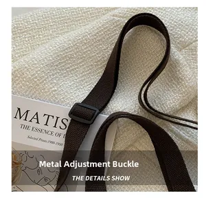 Detail of adjustable black matte buckle on thick brown woven shoulder strap of the bag