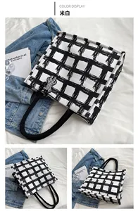 Detail of checkered canvas tote bag in cream white with black rope handles and bear charm