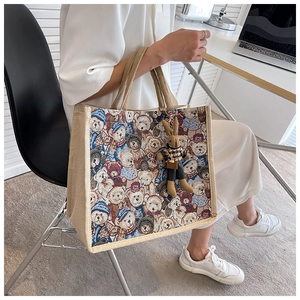 Detail of large tote bag with bear jacquard patterns and rabbit doll accessory