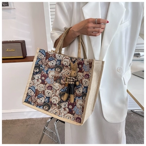 Detail of linen tote bag featuring cartoon bear jacquard pattern and plush bunny pendant